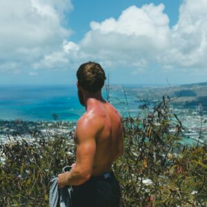 topless man facing sea horizon