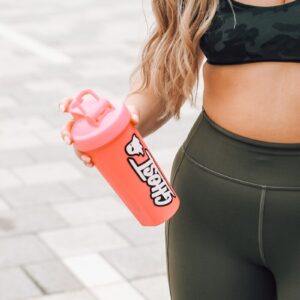 woman in black bra and black leggings holding red and white plastic bottle